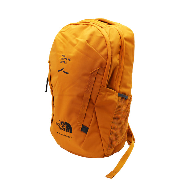 Image of a tan backpack with a black North Face logo and Santa Fe Opera logo. Side mesh pocket and zipper closures.
