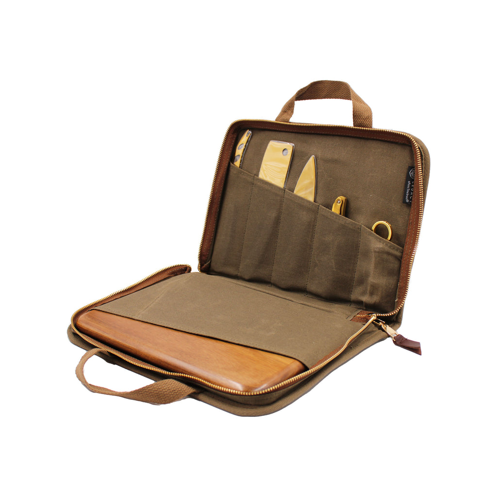 Khaki green zipper bag with a cheese board and brass-toned knife set inside.