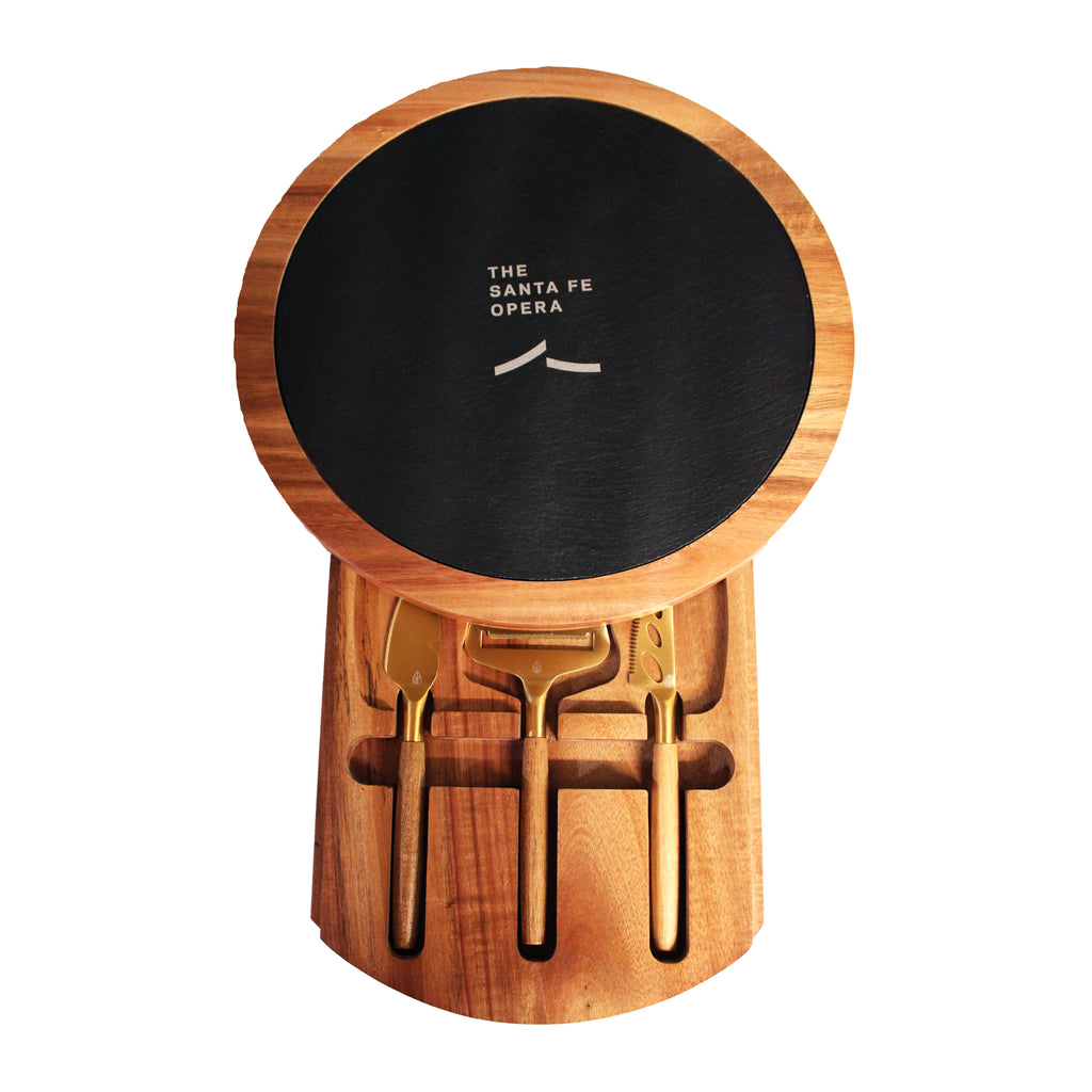 Wooden cheese set with black wheel and gold tools featuring the Santa Fe Opera logo.