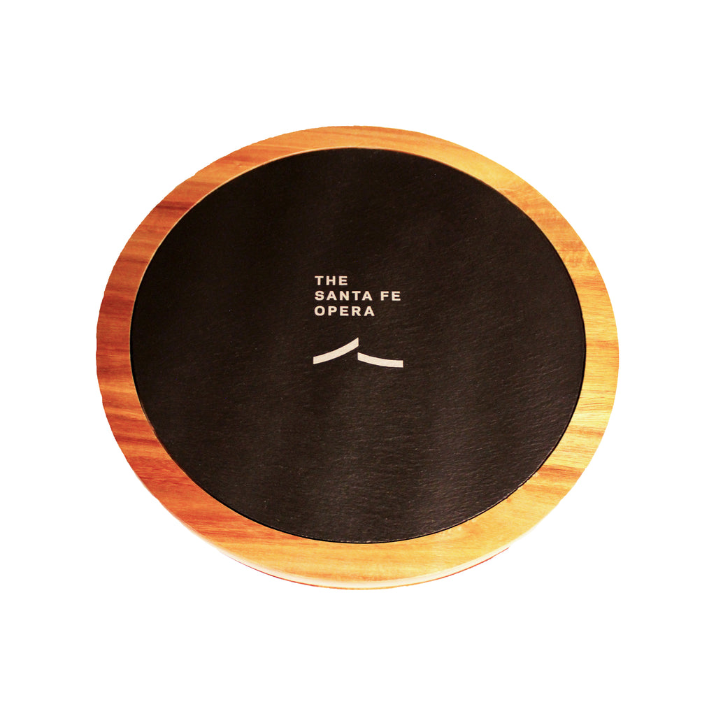 Round wooden board with black center and the Santa Fe Opera logo.