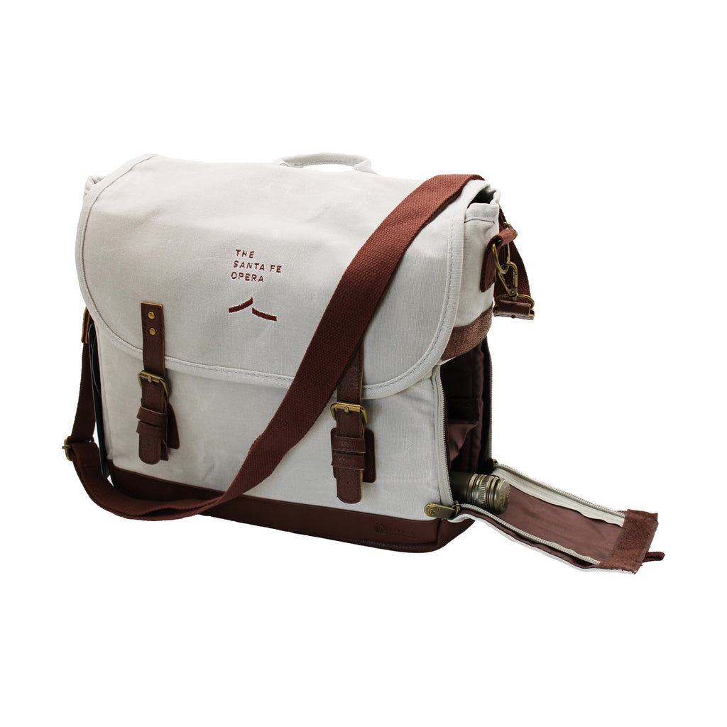 Image of an off-white canvas tote bag with brown accents and wine bottle pocket on the side.